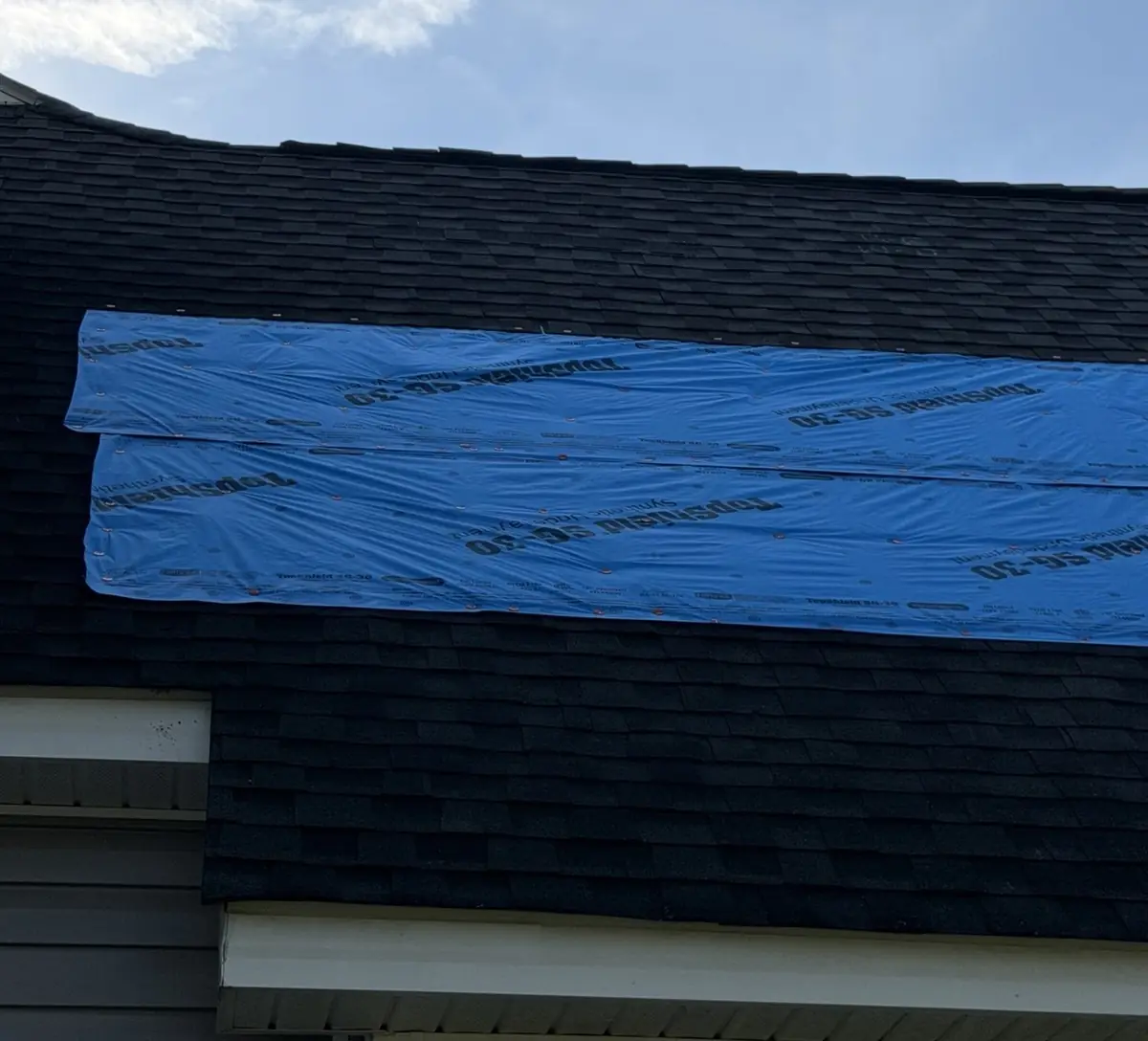 Close-up of a tarp covering damaged shingles on a Benson, North Carolina roof, before replacement