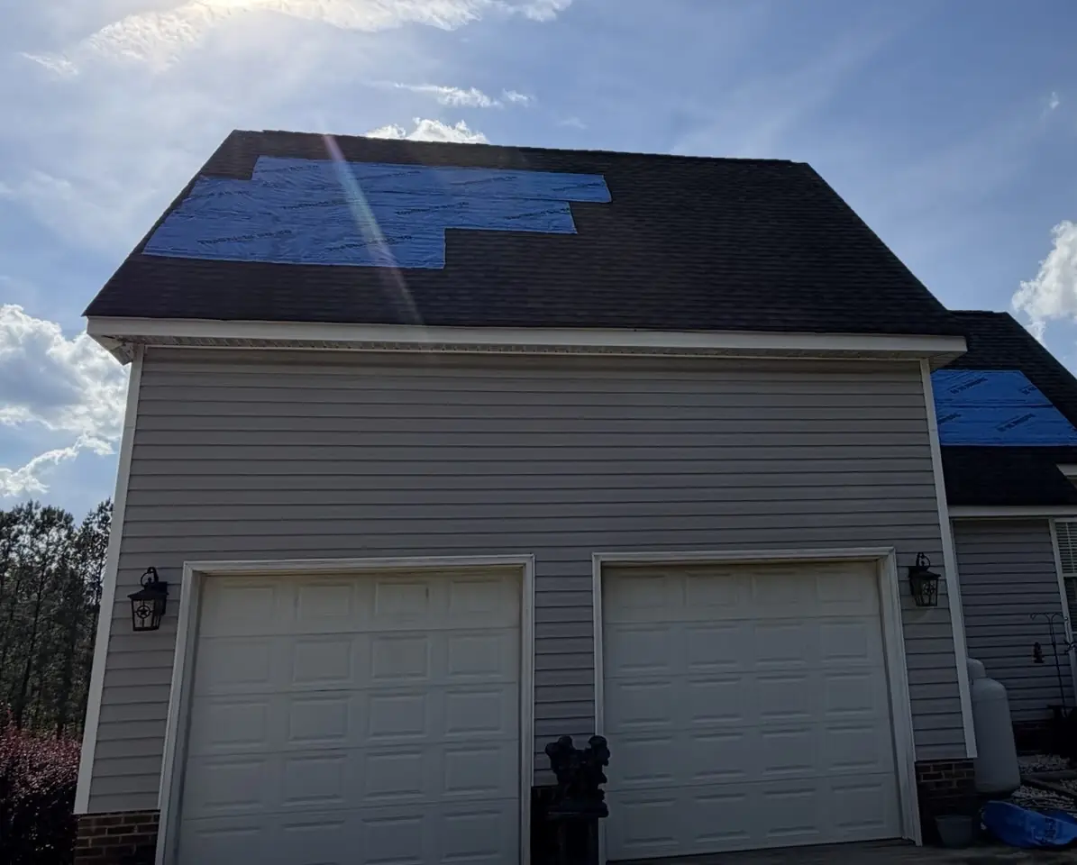Blue tarps covering damaged sections of the garage and main roof on a Benson, North Carolina home, before replacement