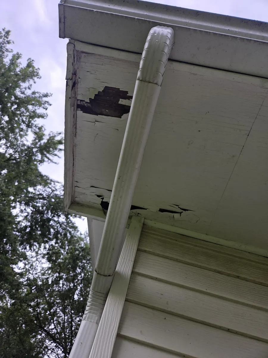 Rotted fascia with a hole behind the downspout on the rear eave in Groveport, Ohio, before repair