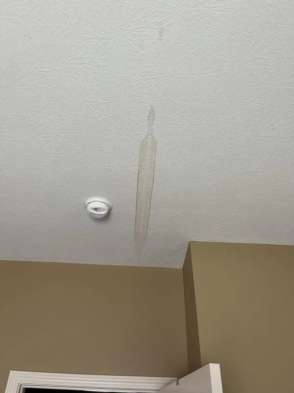 Water stain on a bedroom ceiling below the valley leak in Hilliard, Ohio
