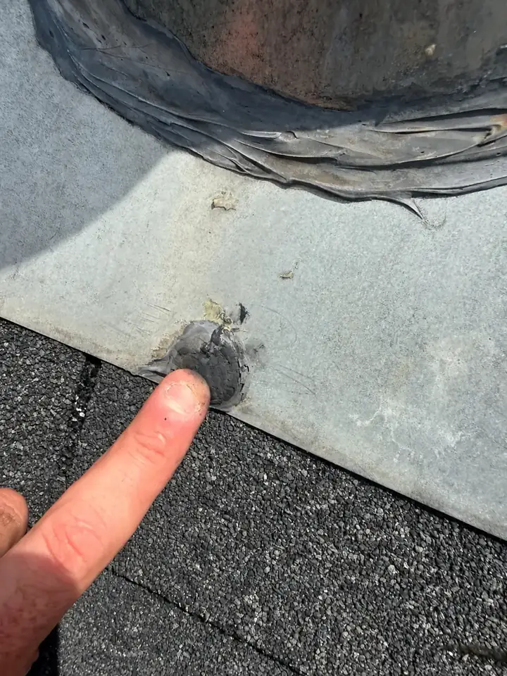 Close-up of a damaged spot around a nail in the vent flashing on a Holly Springs, North Carolina townhome roof, before the leak repair