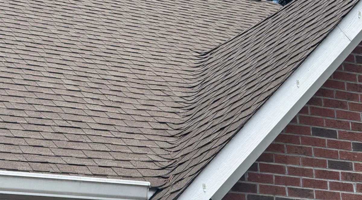 Old shingles where two roof planes meet over brick on a Linden, North Carolina home, before replacement