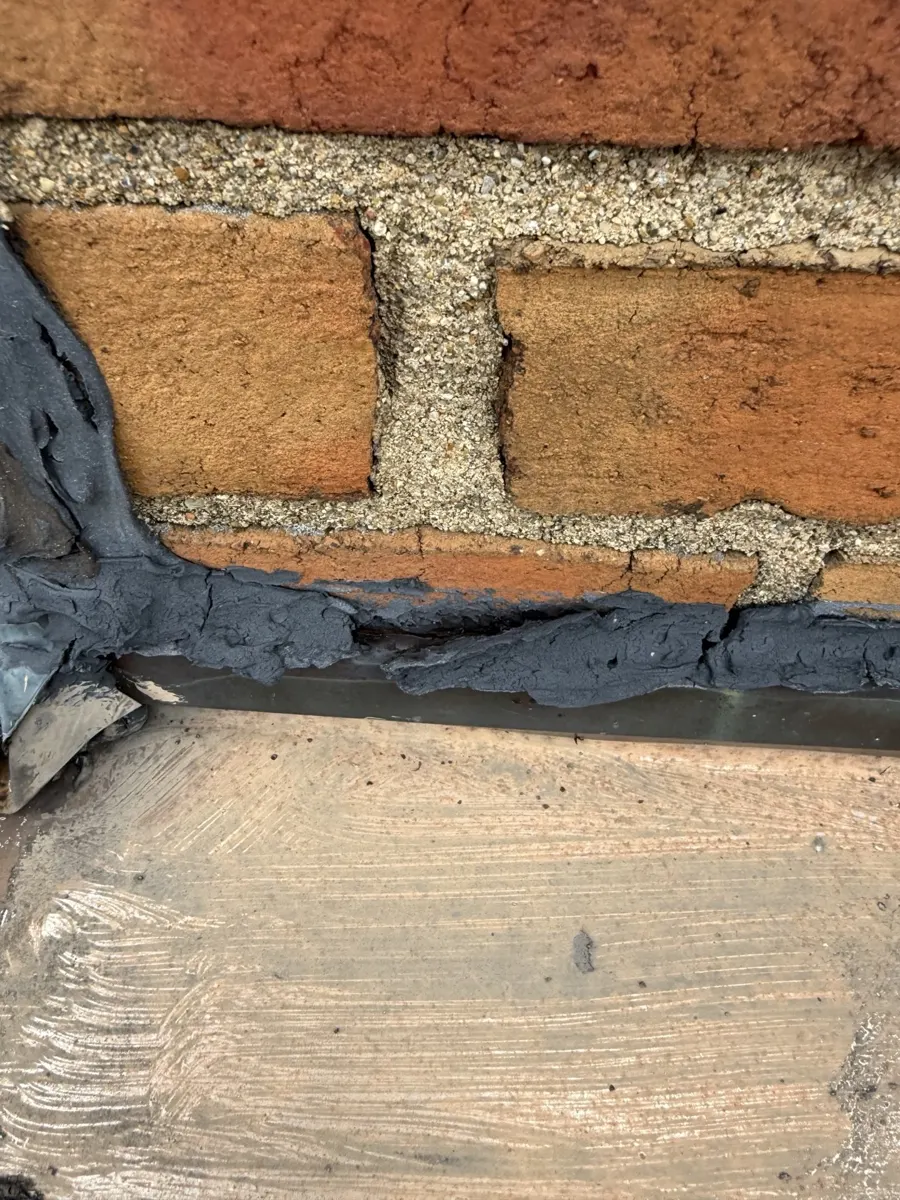 Close-up of the old chimney flashing sealed with tar on the flat roof in New Albany, Ohio, before repair