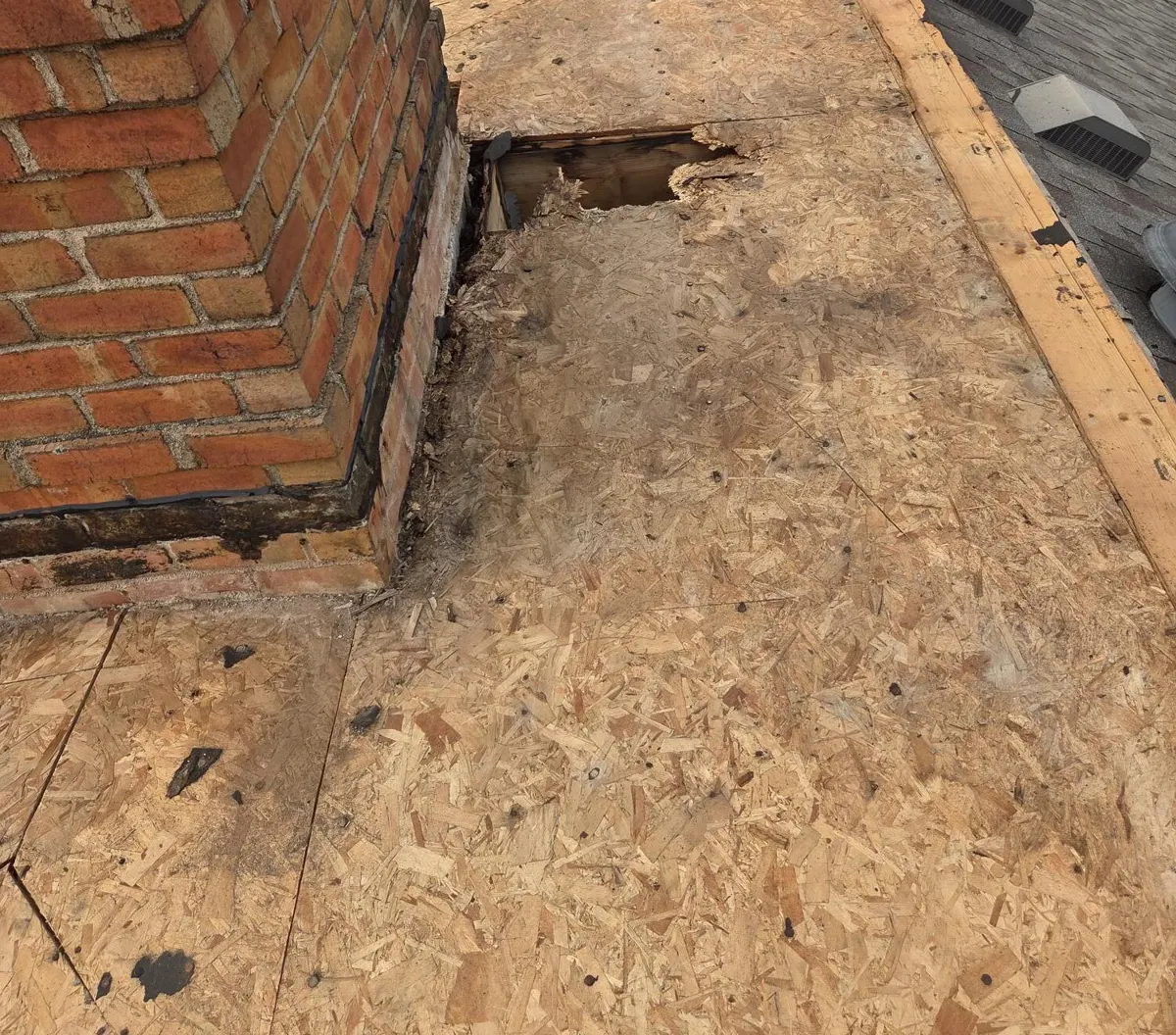 Rotted decking cut out next to the chimney after the old rubber roof was torn off in New Albany, Ohio, during repair