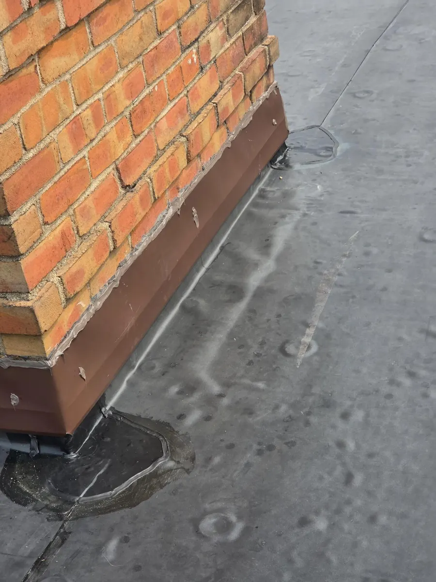 New brown chimney flashing and sealed EPDM membrane at the chimney corner in New Albany, Ohio, after repair