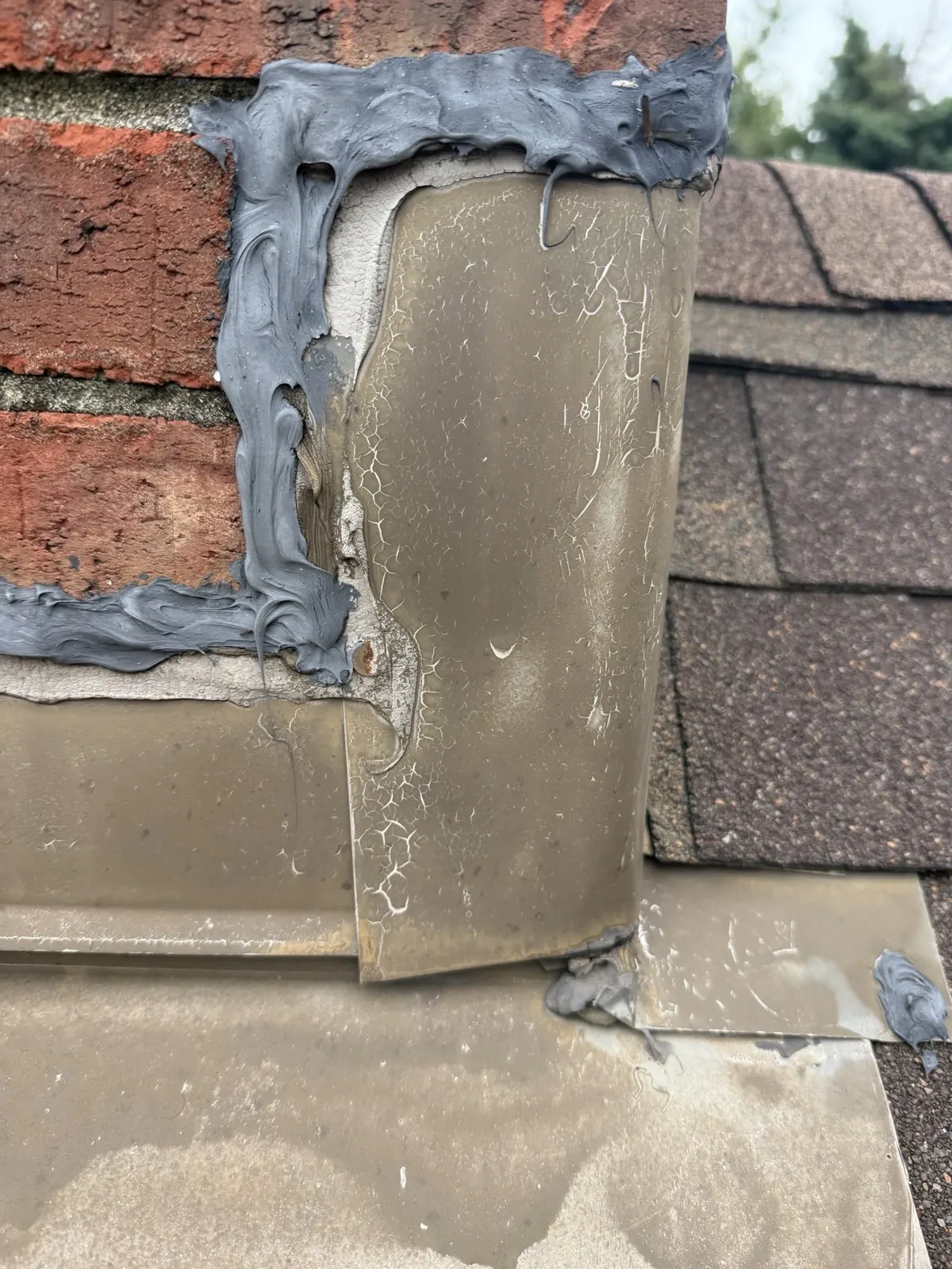 Failed chimney flashing and old sealant at the brick chimney on a Powell, Ohio roof, before repair