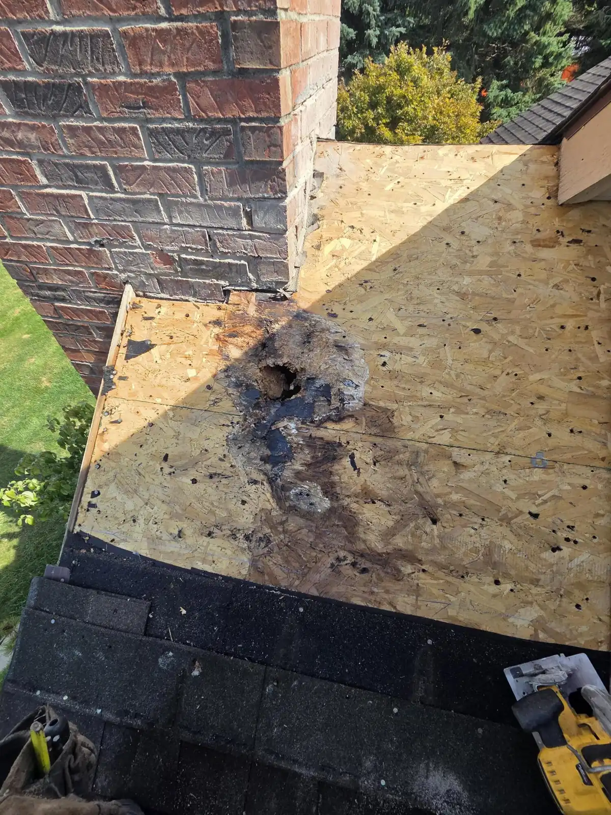 Roof opened at the chimney in Powell, Ohio, showing water-damaged decking during the flashing repair