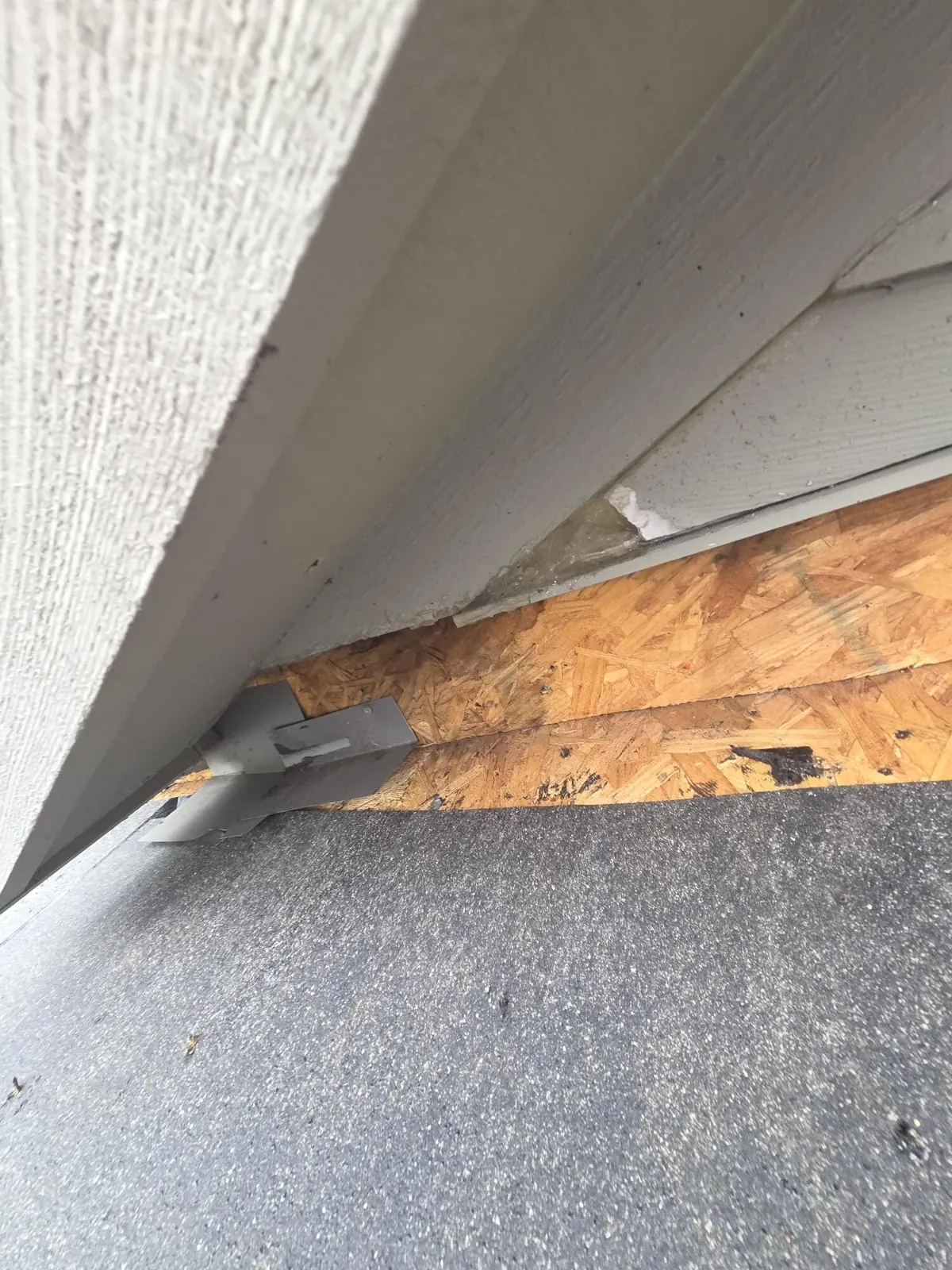 Shingles removed along the sidewall exposing the roof deck during a Powell, Ohio step flashing repair