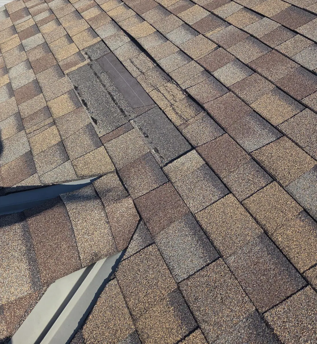 Damaged shingles with missing tabs next to metal flashing in Reynoldsburg, Ohio, before repair